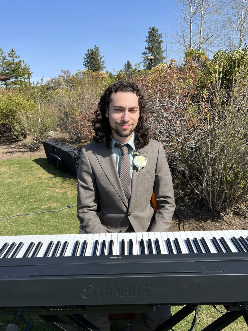 Gabe smiling behind a keyboard outdoors